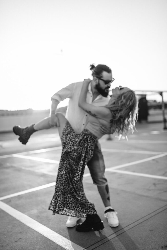 para tańcząca na parkingu na tle zachodzącego słońca zdjęcie czarno białe