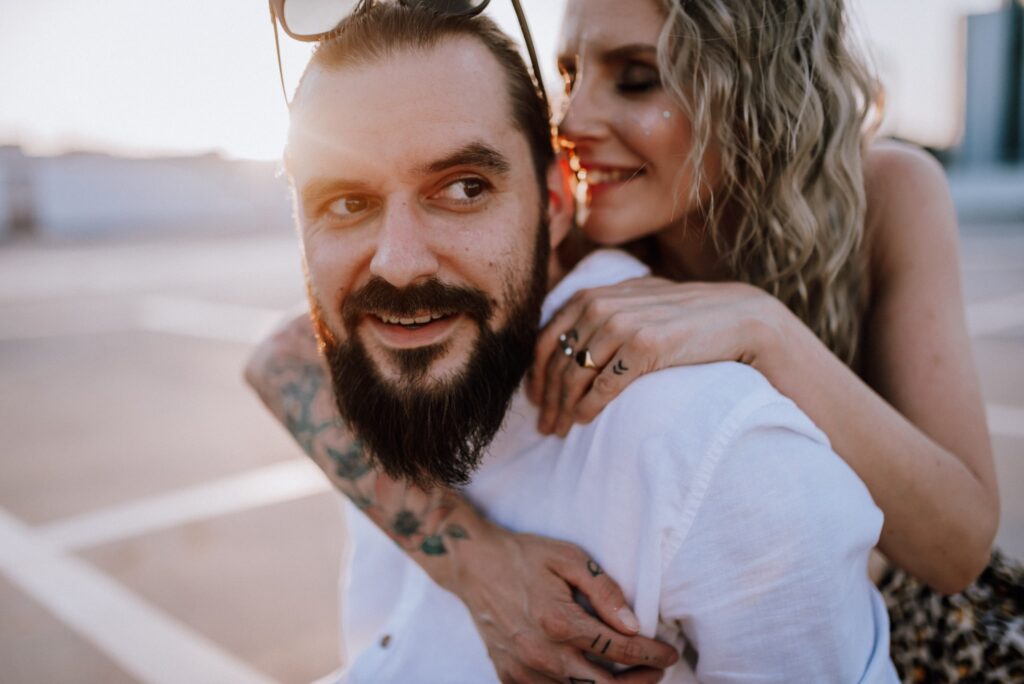 kobieta szepcze do ucha mężczyźnie na tle zachodzącego słońca